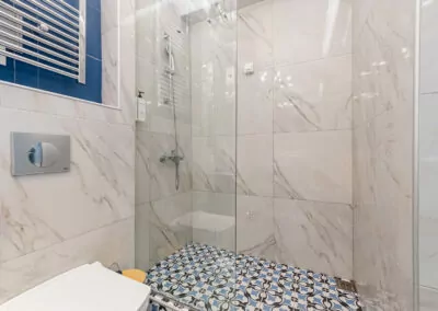Modern marble bathroom with walk-in rain shower and luxury amenities at Alpha Luxury Suites