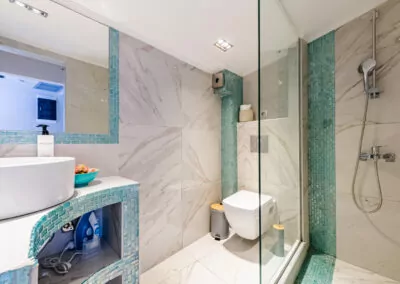 Modern marble bathroom with walk-in rain shower and luxury amenities at Alpha Luxury Suites