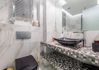 Modern marble bathroom with walk-in rain shower and luxury amenities at Alpha Luxury Suites