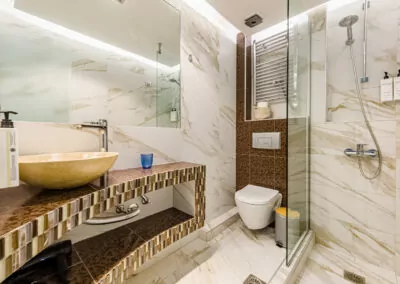 Modern marble bathroom with walk-in rain shower and luxury amenities at Alpha Luxury Suites