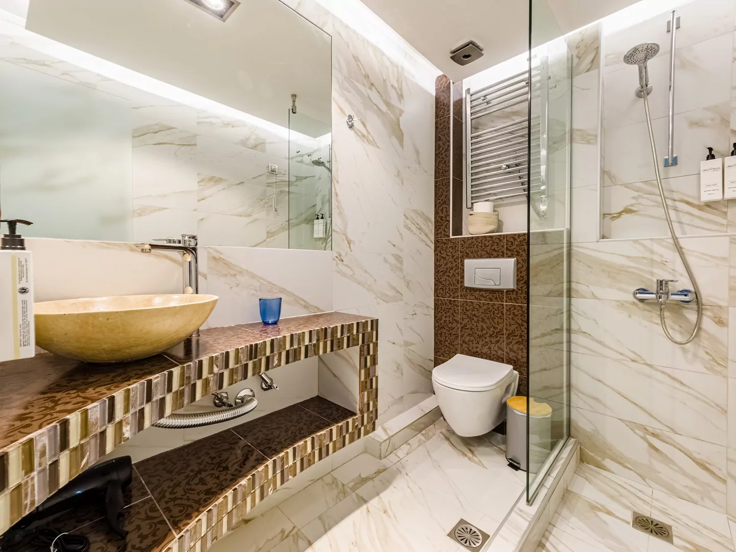 Modern marble bathroom with walk-in rain shower and luxury amenities at Alpha Luxury Suites