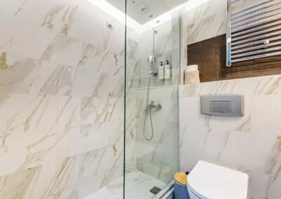 Modern marble bathroom with walk-in rain shower and luxury amenities at Alpha Luxury Suites
