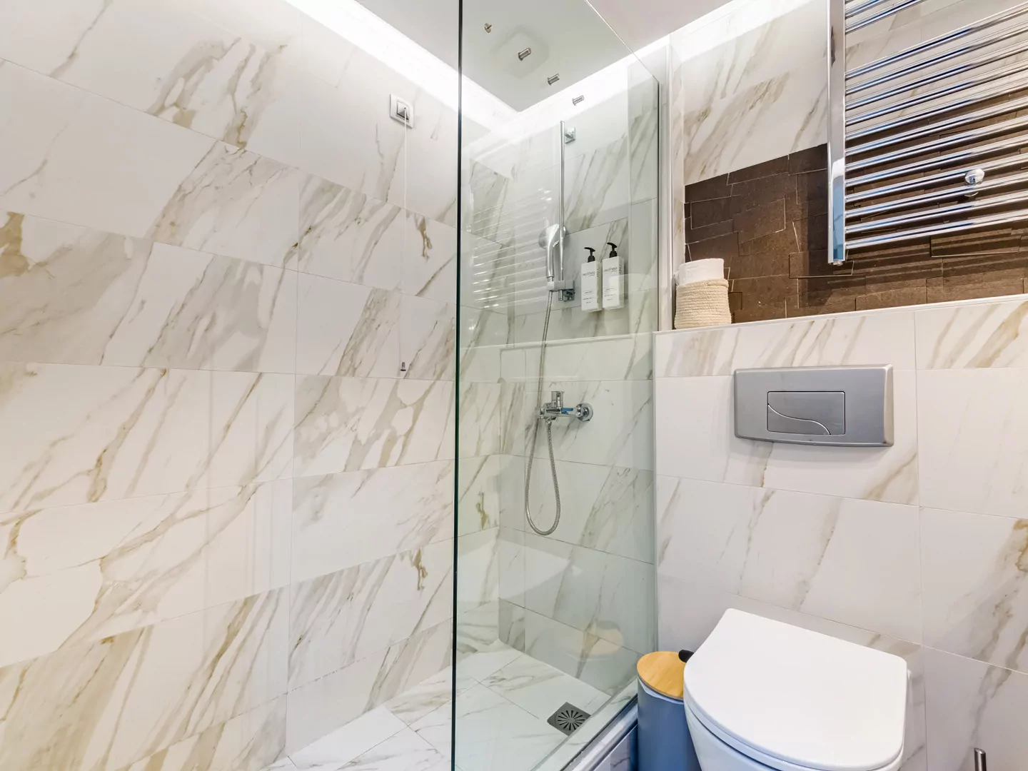 Modern marble bathroom with walk-in rain shower and luxury amenities at Alpha Luxury Suites