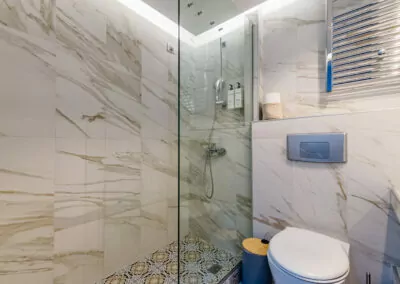 Modern marble bathroom with walk-in rain shower and luxury amenities at Alpha Luxury Suites