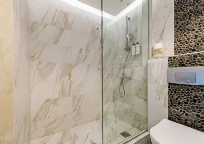 Modern marble bathroom with walk-in rain shower and luxury amenities at Alpha Luxury Suites