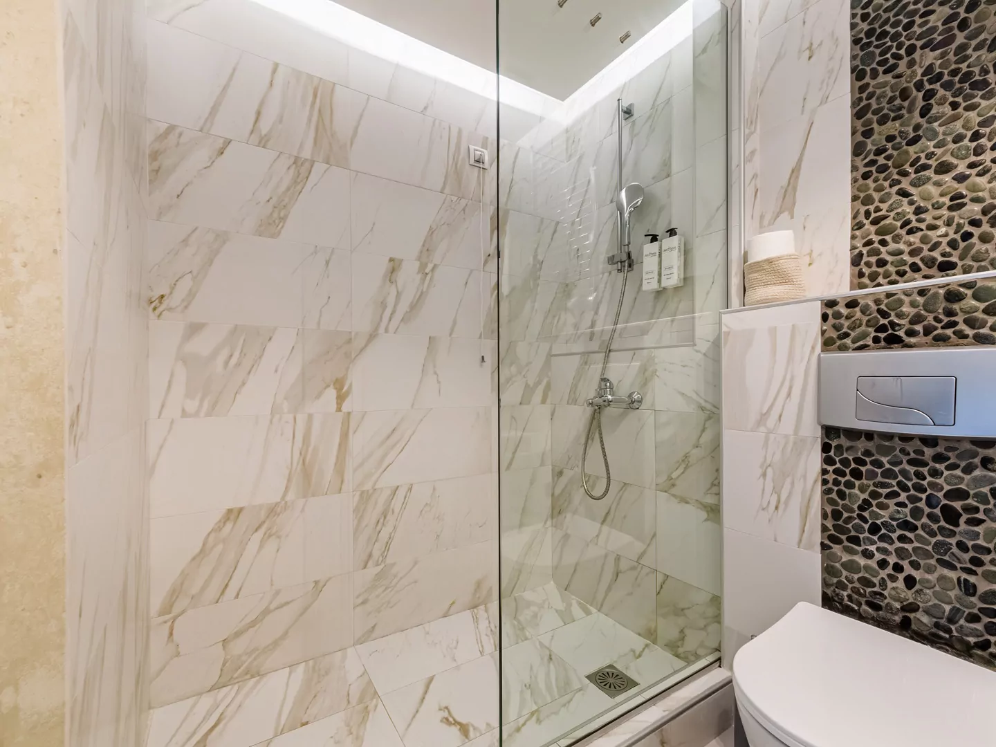 Modern marble bathroom with walk-in rain shower and luxury amenities at Alpha Luxury Suites