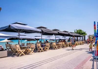 Beachfront lounge area with black umbrellas and crystal clear water at Alpha Luxury Suites Pefkohori